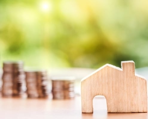 Small wooden house in front of piles of coins