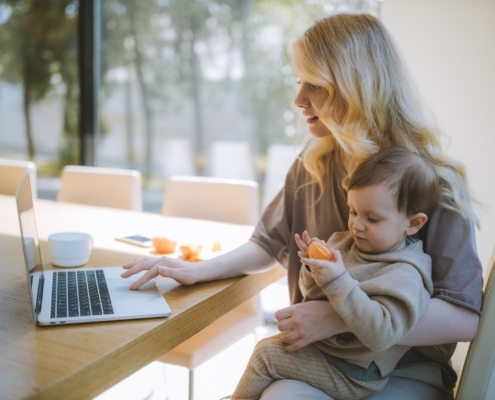 Mother holding a baby while working remotely