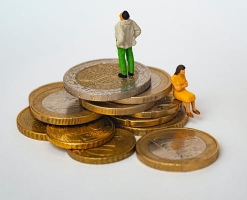 Toy figures standing on a pile of euro coins