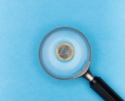 euro coin under a magnifying glass to symbolize pay transparency
